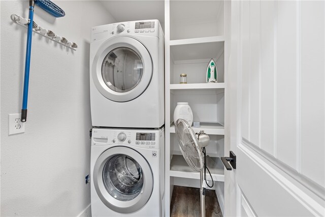 clothes washing area with stacked washer and dryer and dark wood-type flooring