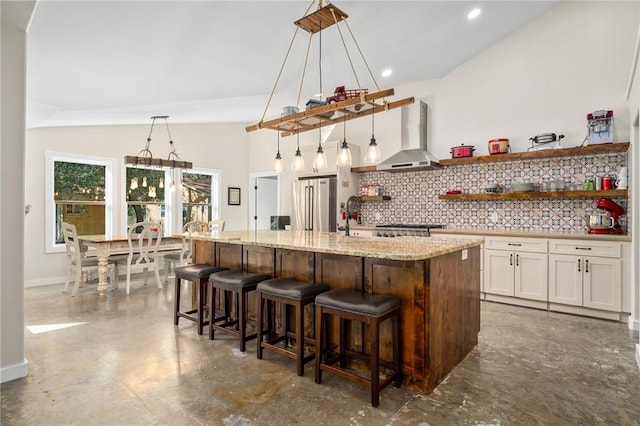 kitchen featuring backsplash, a kitchen island with sink, hanging light fixtures, and vaulted ceiling