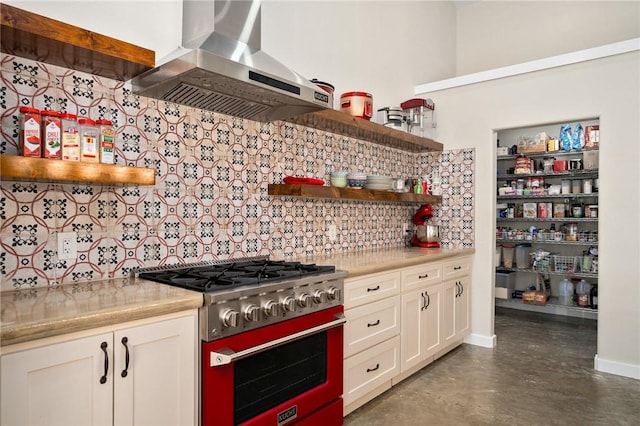 kitchen with tasteful backsplash, white cabinetry, high end stainless steel range, and ventilation hood