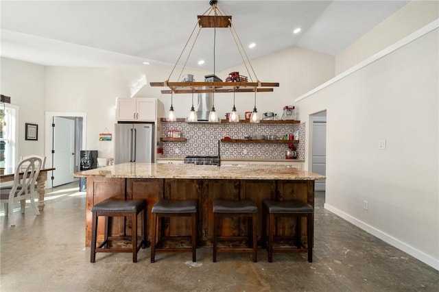 kitchen featuring a center island, decorative light fixtures, high end fridge, and a kitchen breakfast bar