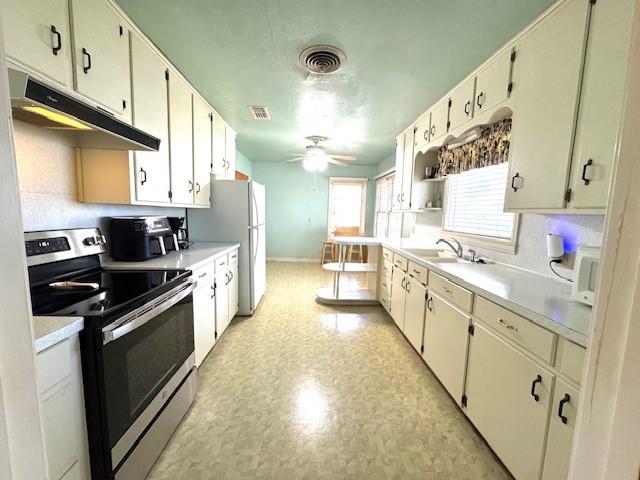 kitchen with visible vents, under cabinet range hood, light countertops, stainless steel electric range, and a sink