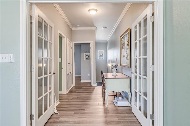 hall with ornamental molding, french doors, and light hardwood / wood-style floors