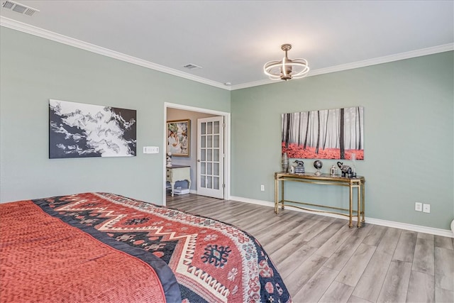 bedroom with ornamental molding, french doors, hardwood / wood-style flooring, and an inviting chandelier