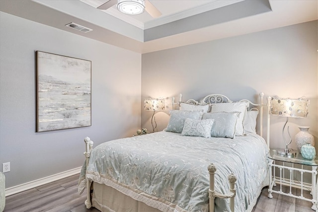 bedroom with dark wood-type flooring, ceiling fan, and a raised ceiling