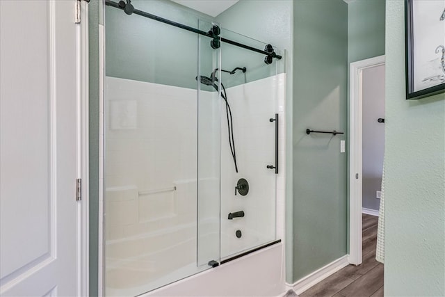 bathroom with bath / shower combo with glass door and hardwood / wood-style flooring