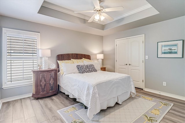 bedroom with hardwood / wood-style flooring, ceiling fan, a raised ceiling, and a closet