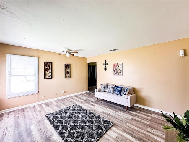 living room with visible vents, baseboards, light wood-style flooring, and ceiling fan
