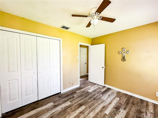 unfurnished bedroom featuring ceiling fan, a closet, visible vents, dark wood-style flooring, and baseboards