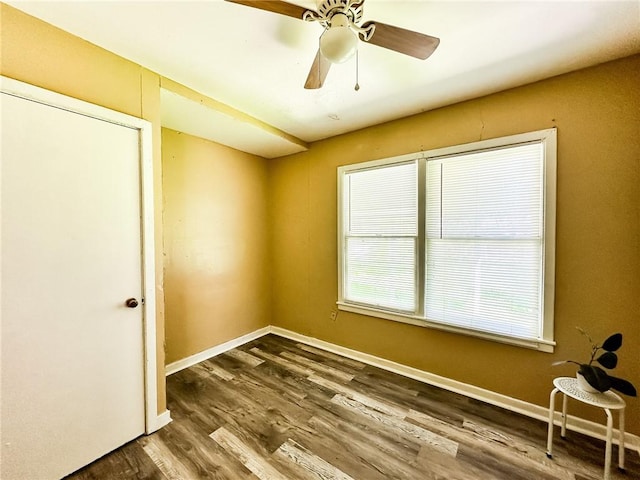 empty room featuring dark wood-type flooring, baseboards, and a ceiling fan