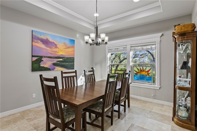 dining space with a chandelier, a raised ceiling, and crown molding