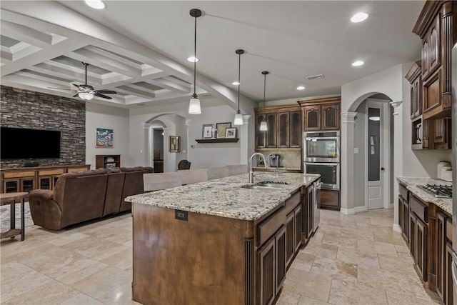 kitchen with hanging light fixtures, coffered ceiling, a kitchen island with sink, beam ceiling, and appliances with stainless steel finishes