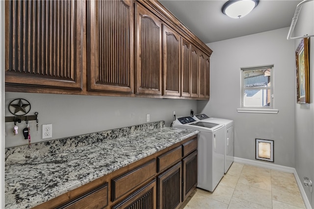 clothes washing area featuring light tile patterned floors, cabinets, and washing machine and clothes dryer