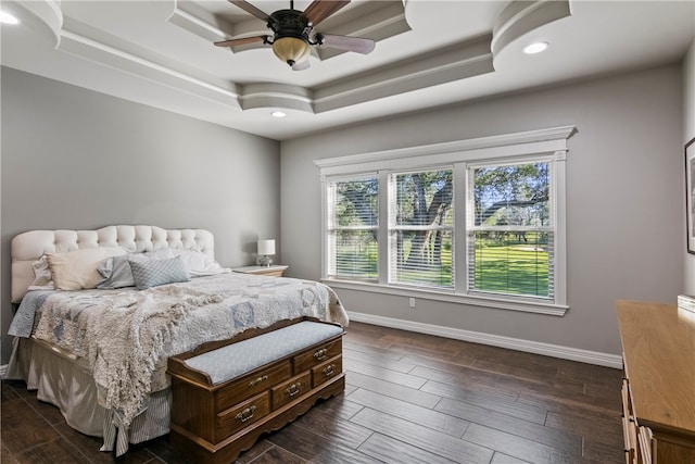 bedroom with dark wood-type flooring, ceiling fan, and a raised ceiling