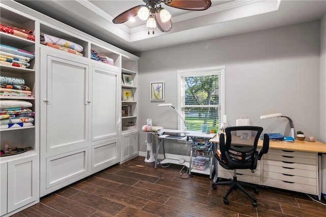 office area with dark wood-type flooring, ceiling fan, a tray ceiling, and ornamental molding