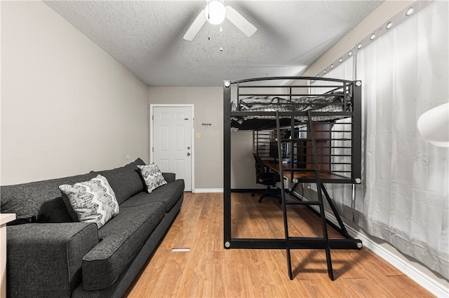 bedroom with ceiling fan, wood-type flooring, and a textured ceiling