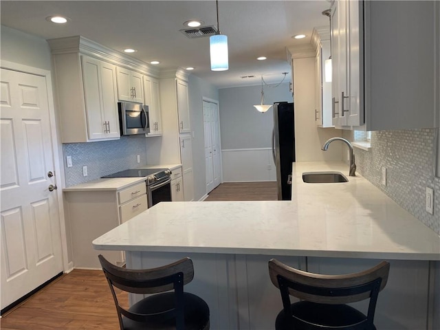 4513 Snead Dr, Corpus Christi, TX 78413 - kitchen with stainless steel appliances, a sink, decorative backsplash, a peninsula, and white cabinetry