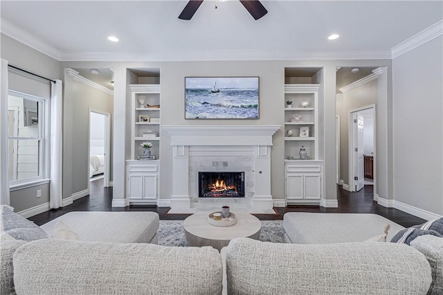 living room featuring built in shelves, dark hardwood / wood-style flooring, ceiling fan, and ornamental molding