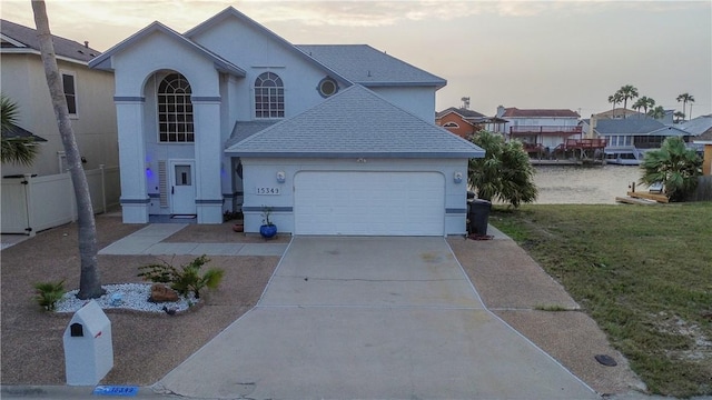 view of front of property featuring stucco siding, a front yard, an attached garage, a shingled roof, and concrete driveway