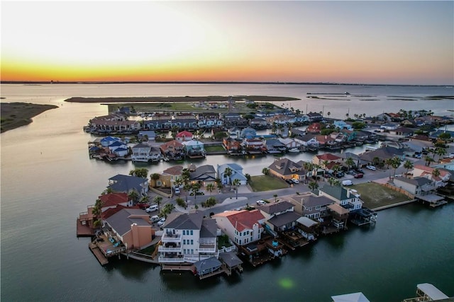 aerial view at dusk featuring a water view and a residential view