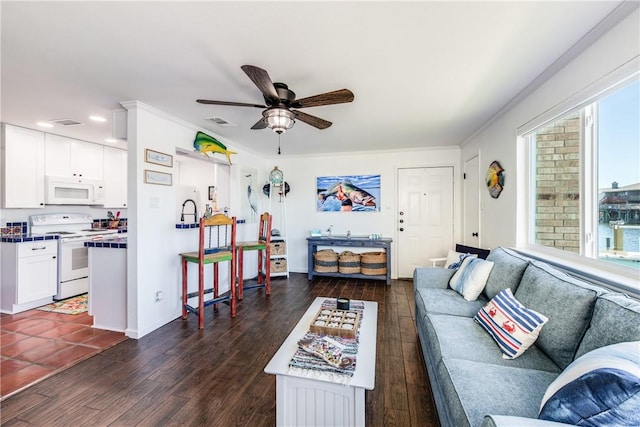 living room with ceiling fan, ornamental molding, dark wood-type flooring, and a brick fireplace