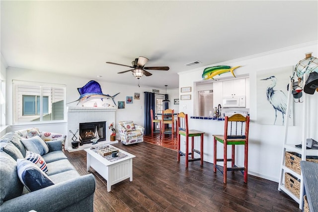 living room featuring a water view, ornamental molding, dark hardwood / wood-style floors, and a brick fireplace