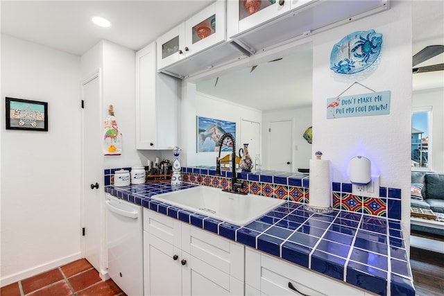 kitchen featuring white cabinets, tile counters, dishwasher, and sink