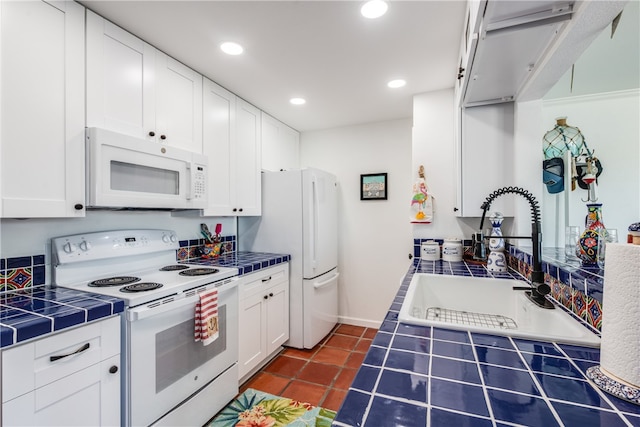 kitchen featuring white appliances, dark tile patterned flooring, sink, tile counters, and white cabinetry