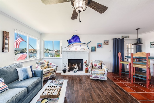 living room featuring a fireplace, dark hardwood / wood-style flooring, ceiling fan, and crown molding