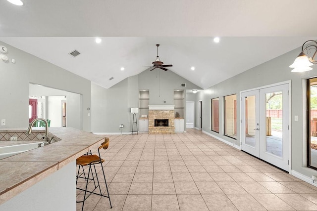 2214 N Mccampbell St, Aransas Pass, TX 78336 - kitchen featuring a ceiling fan, light tile patterned floors, a kitchen bar, a stone fireplace, and recessed lighting