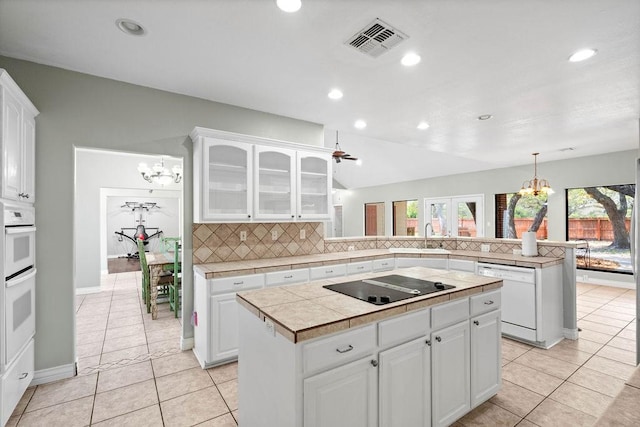 2214 N Mccampbell St, Aransas Pass, TX 78336 - kitchen with a chandelier, white appliances, a peninsula, tasteful backsplash, and glass insert cabinets