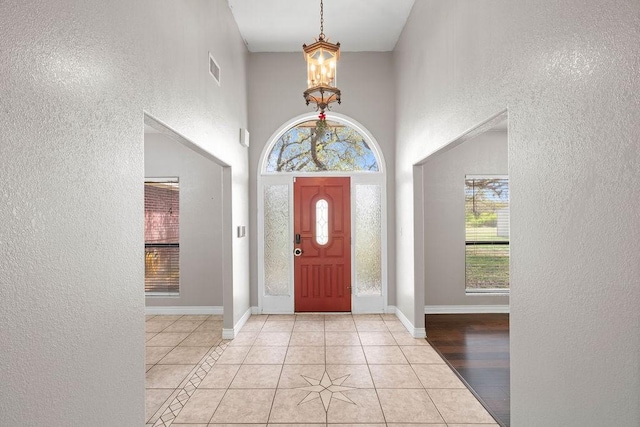 2214 N Mccampbell St, Aransas Pass, TX 78336 - entryway featuring a chandelier, a textured wall, healthy amount of natural light, light tile patterned floors, and a towering ceiling