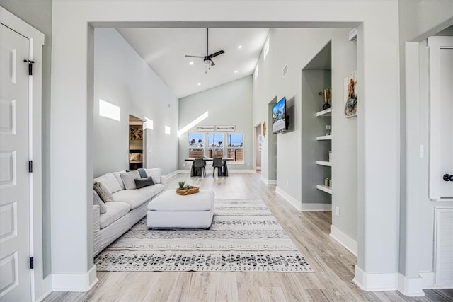 living area featuring recessed lighting, a high ceiling, baseboards, and wood finished floors