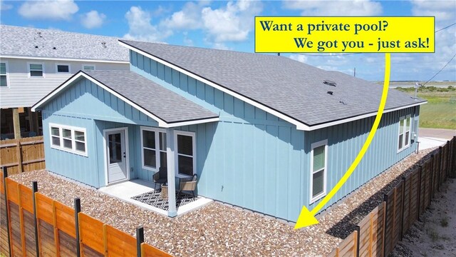 1931 Eskridge St, Port Aransas, TX 78373 - view of front of house featuring roof with shingles, a fenced backyard, a patio area, and board and batten siding