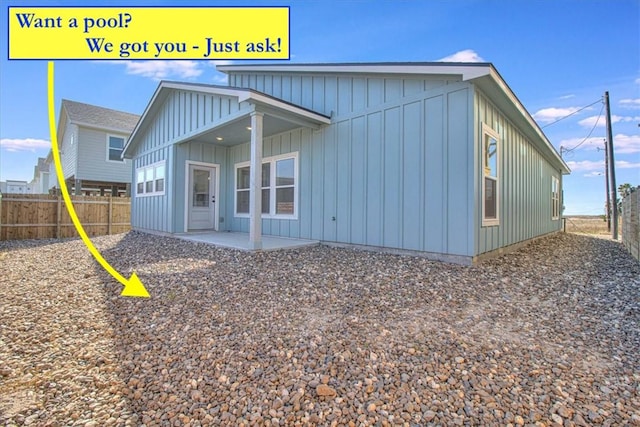 back of property with board and batten siding, a patio area, and fence