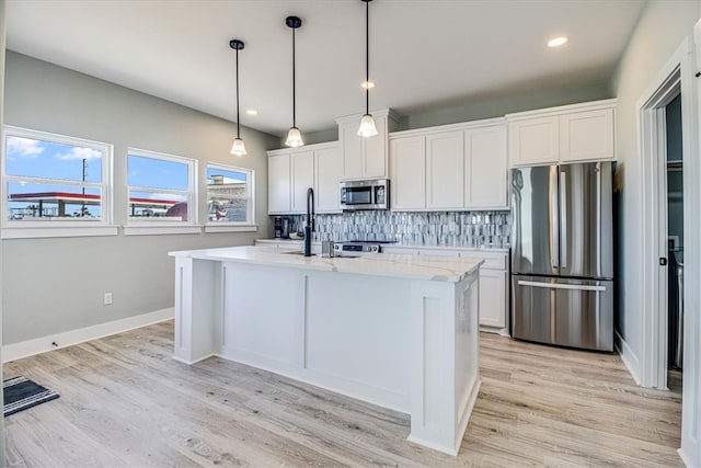 kitchen featuring a kitchen island with sink, tasteful backsplash, light wood-type flooring, stainless steel appliances, and white cabinetry