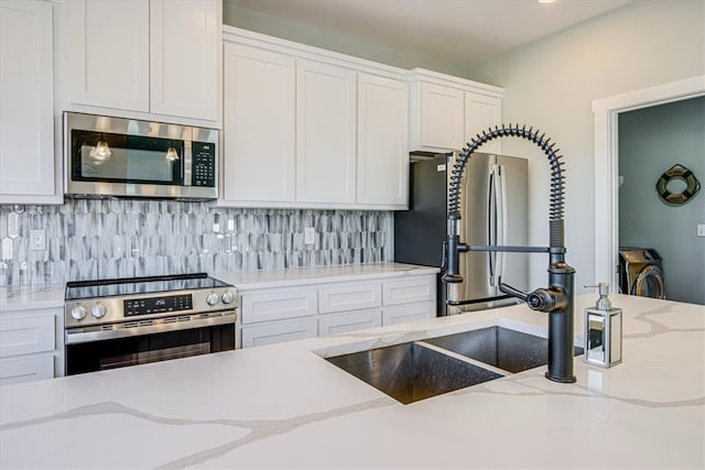 kitchen featuring white cabinetry, appliances with stainless steel finishes, light stone counters, and backsplash