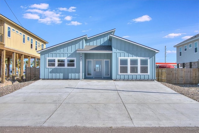 back of property with board and batten siding, fence, driveway, and roof with shingles