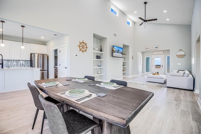 dining space featuring baseboards, visible vents, a ceiling fan, light wood-style flooring, and built in shelves