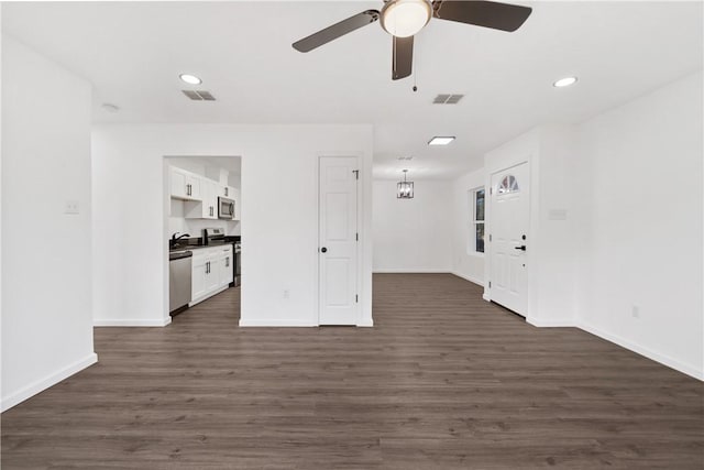 unfurnished living room featuring dark hardwood / wood-style flooring and ceiling fan with notable chandelier