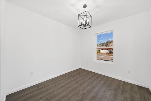 empty room with dark hardwood / wood-style floors and a notable chandelier