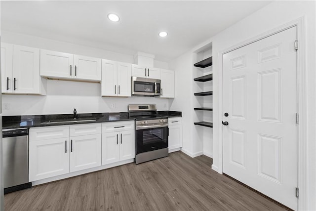 kitchen with wood-type flooring, sink, stainless steel appliances, and white cabinetry