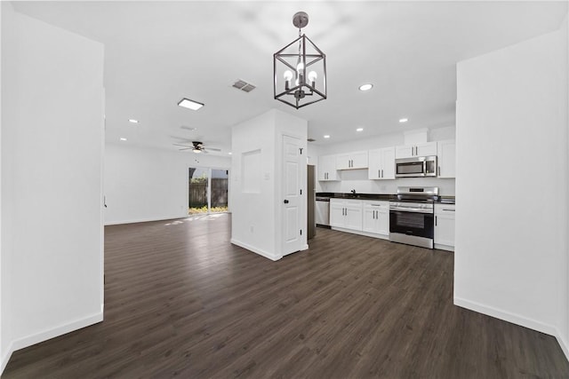 kitchen with decorative light fixtures, appliances with stainless steel finishes, white cabinets, dark hardwood / wood-style flooring, and ceiling fan with notable chandelier