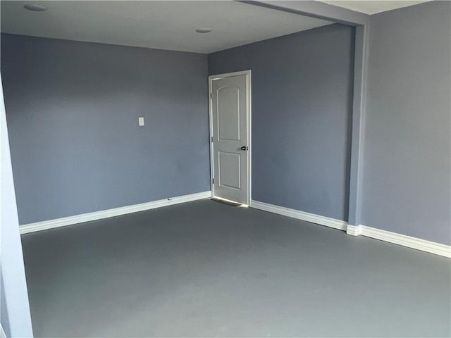 unfurnished room with baseboards and concrete flooring