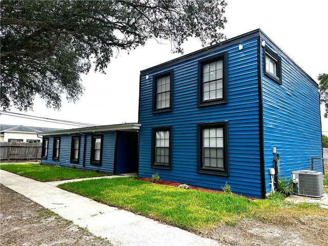 view of front of home featuring fence, central AC unit, and a front yard