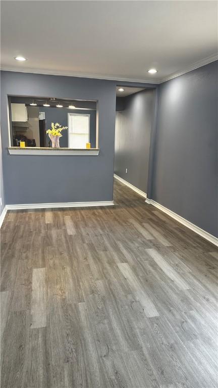 interior space with ornamental molding, wood finished floors, and baseboards