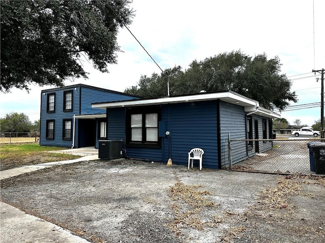 view of front of house with driveway, fence, and central air condition unit