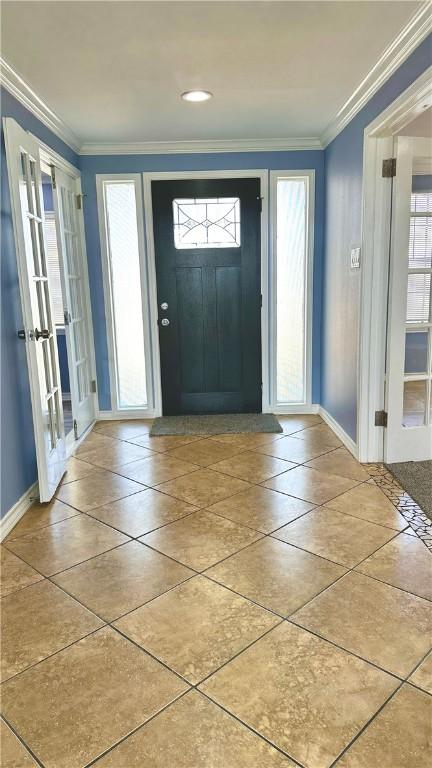 tiled entryway featuring a healthy amount of sunlight, baseboards, and crown molding