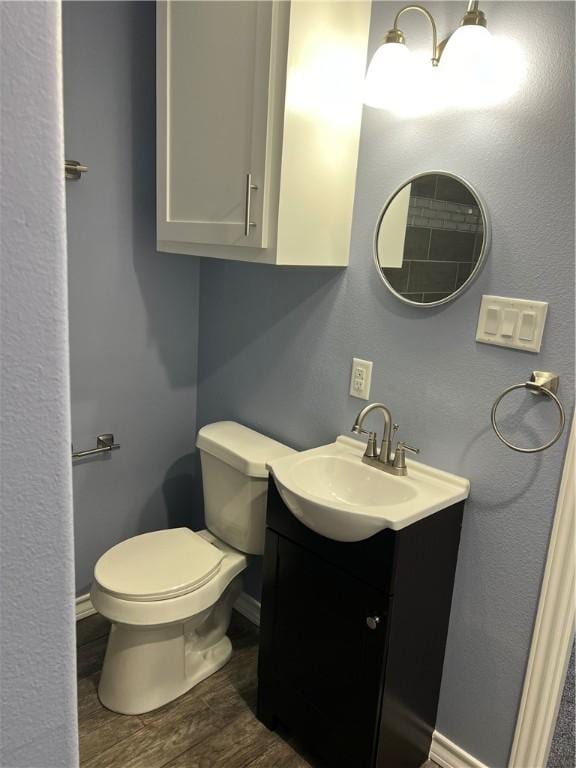 bathroom with baseboards, vanity, toilet, and wood finished floors