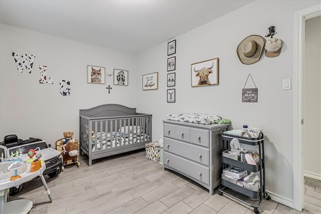 bedroom with light wood-type flooring and a crib