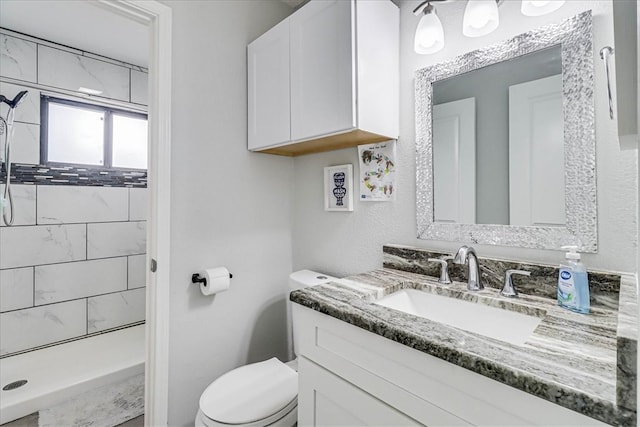 bathroom with vanity, toilet, and a tile shower